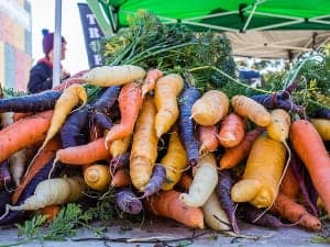 Multi-coloured carrots stacked on a stall at the Carlton Farmers Market