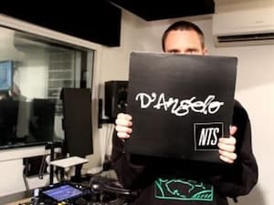 Photo of a person holding up a vinyl record with radio station equipment in the background